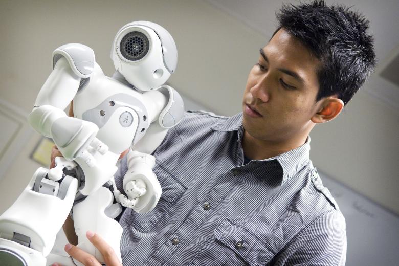 A student examining a humanoid robot